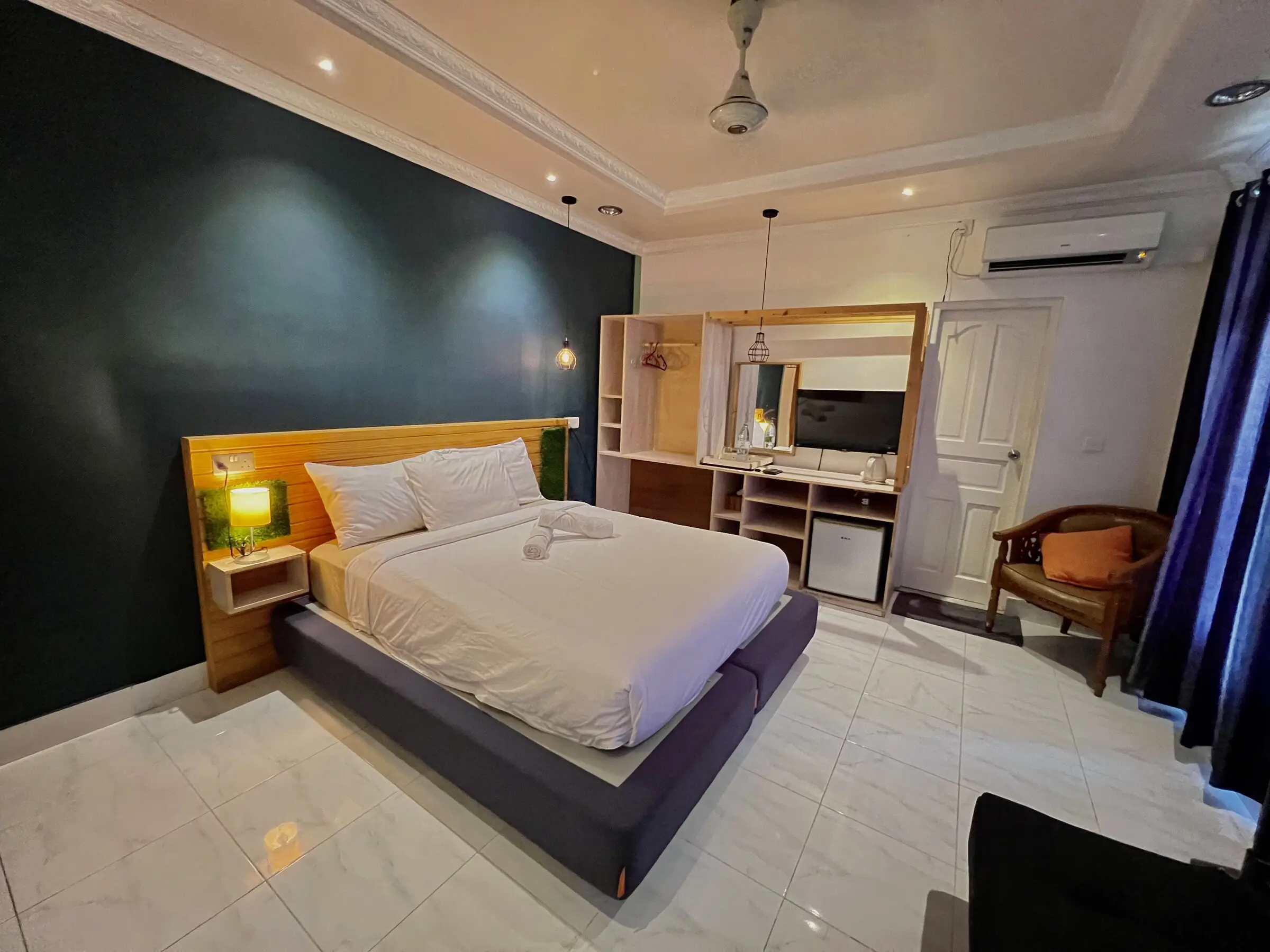 Room with a dark feature wall, double bed and bedside lamps at Koimala Maamigili