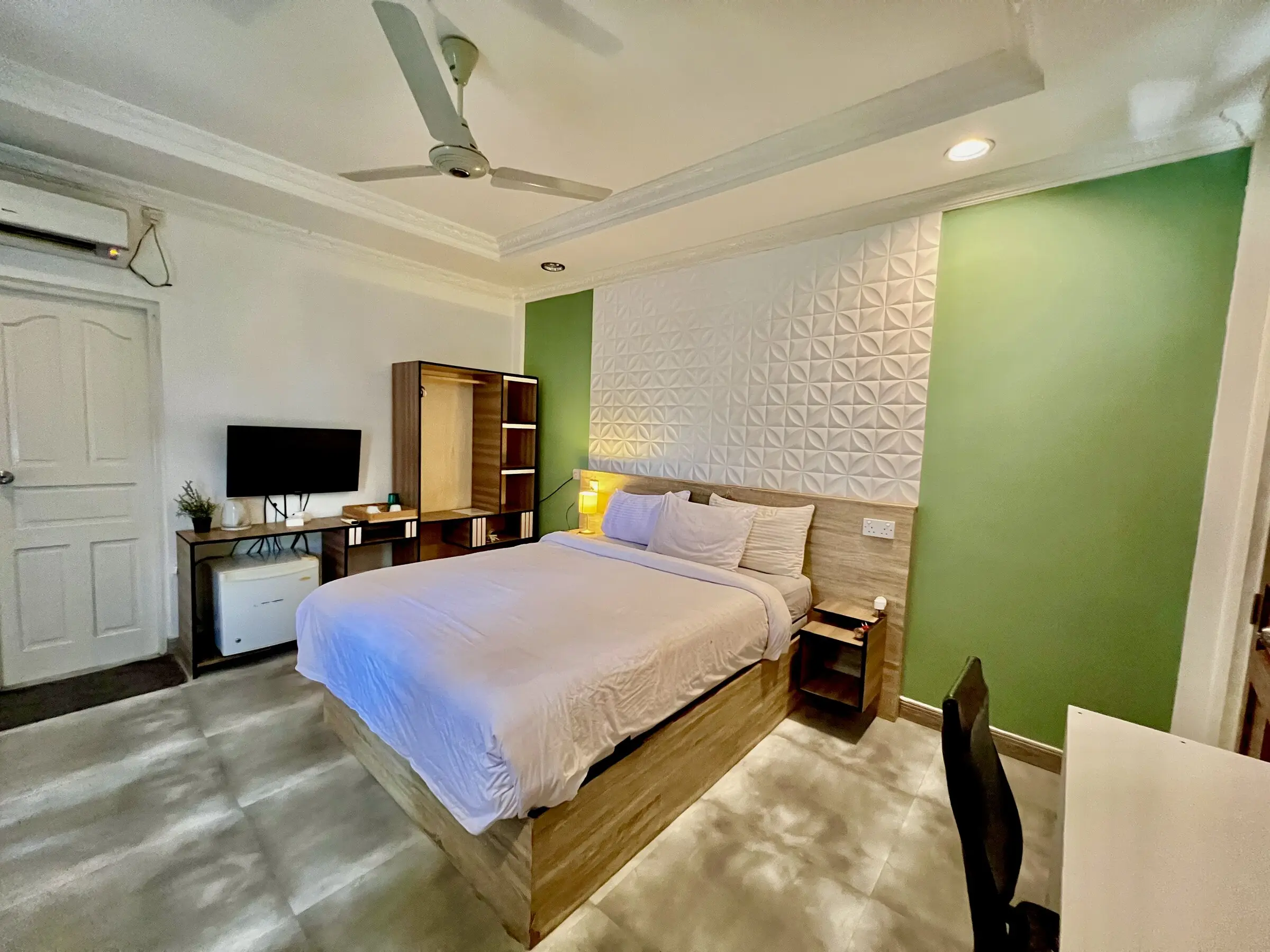 Room with a green wall and wall-mounted TV at Koimala Maamigili