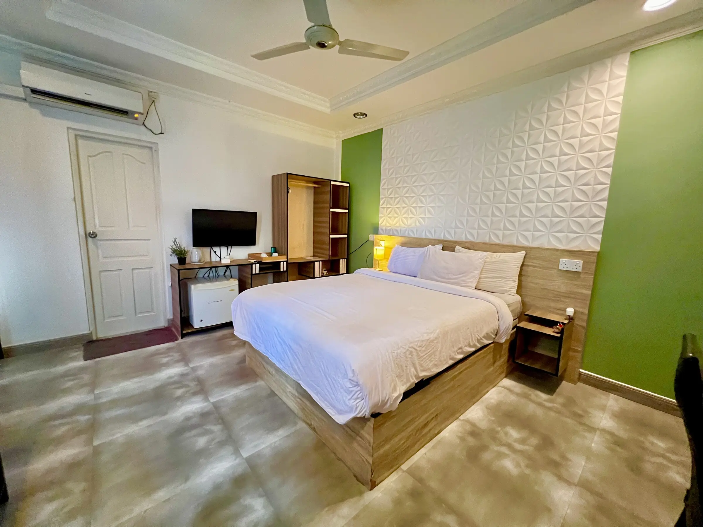 Double bed against a green feature wall at Koimala Maamigili