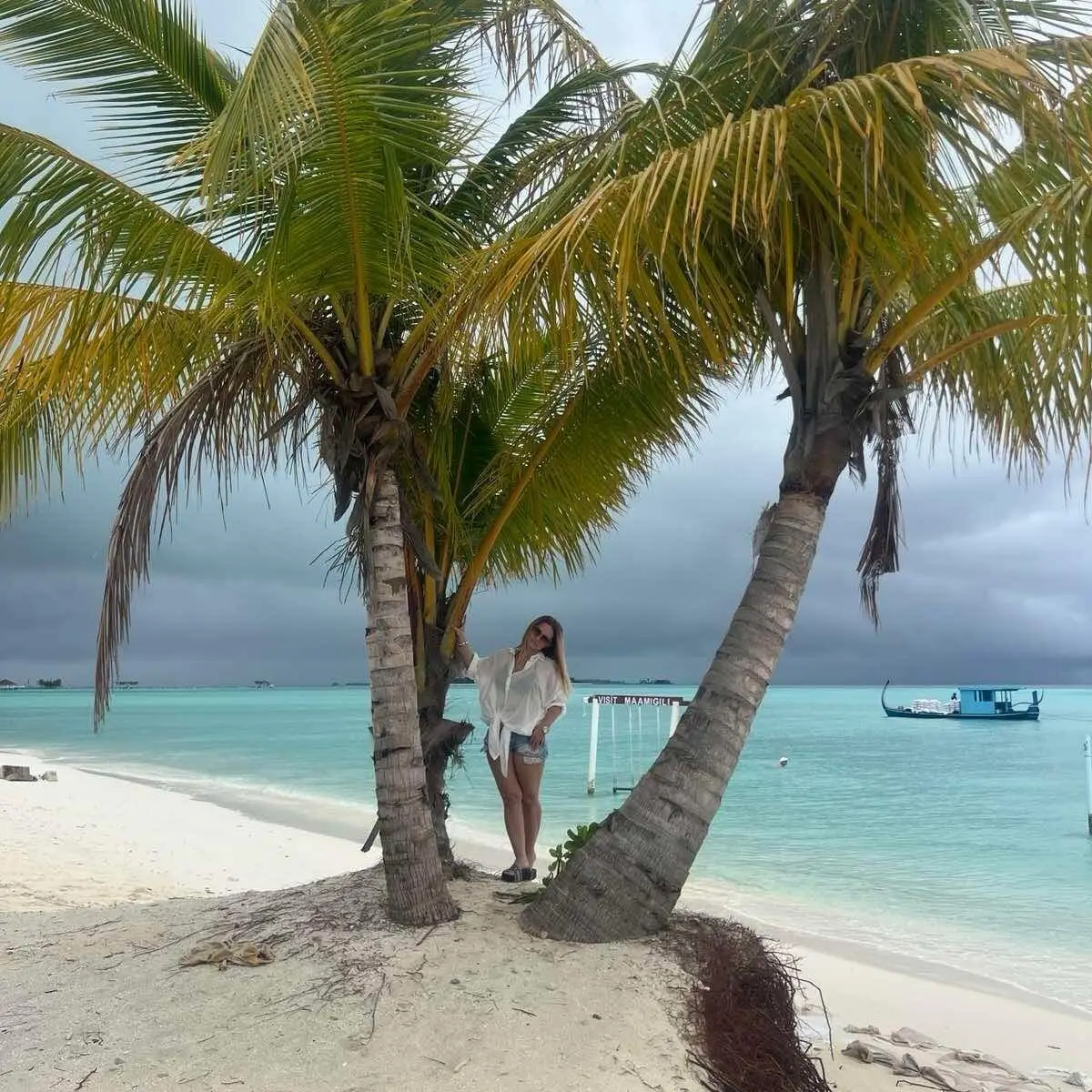 Couple with a paddleboard beside a palm on Maamigili beach