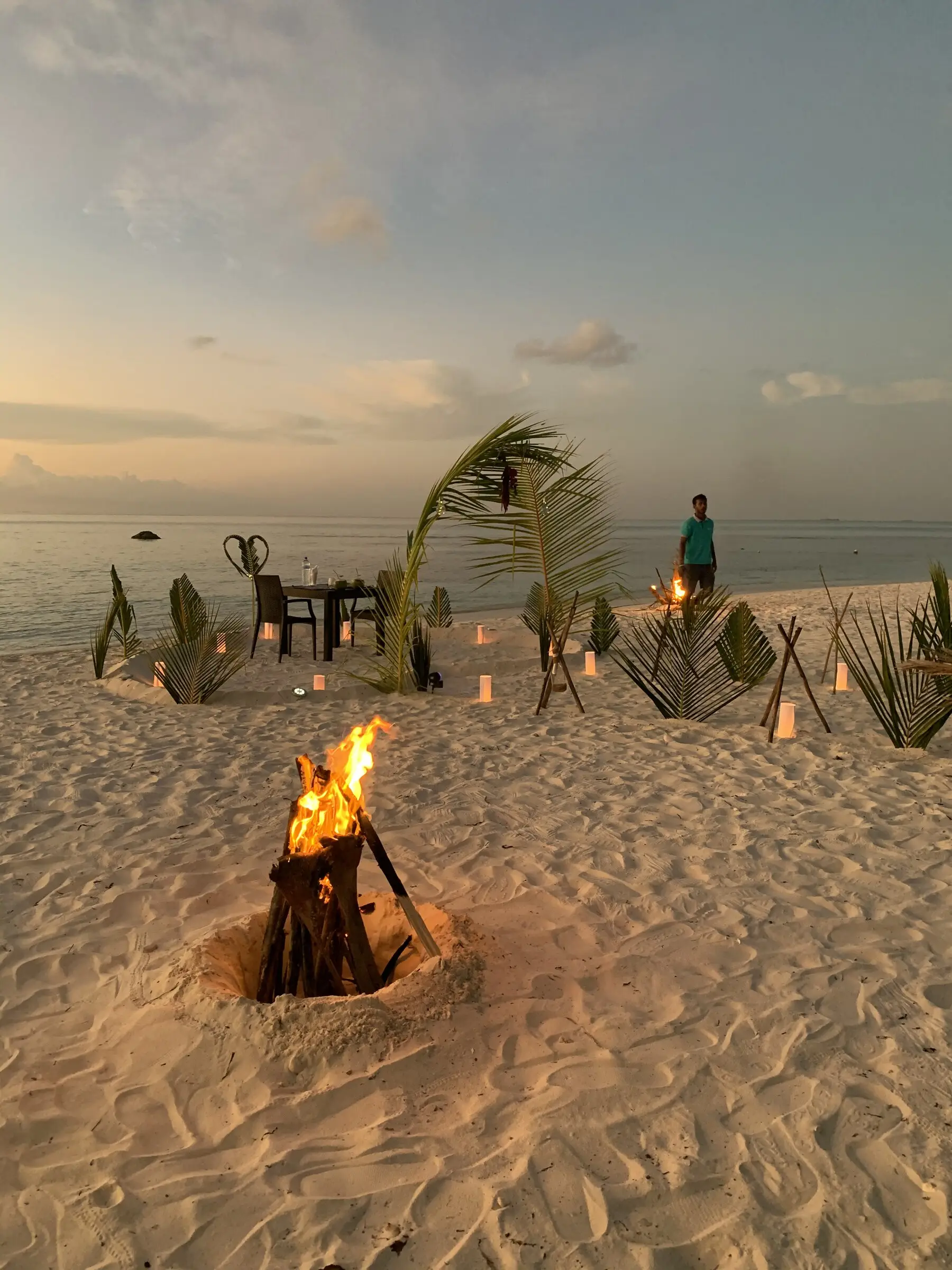 Private beach bonfire and dinner setup at sunset on Maamigili