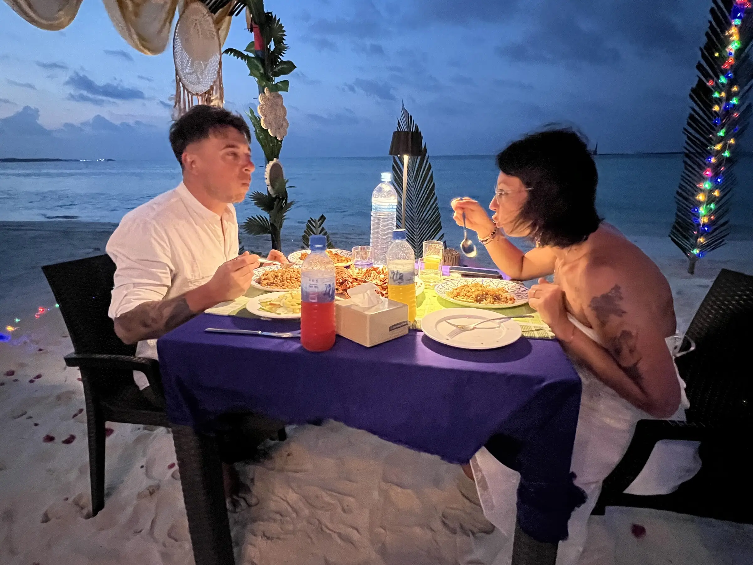 Guests enjoying a meal at a beachside table at Koimala Maamigili